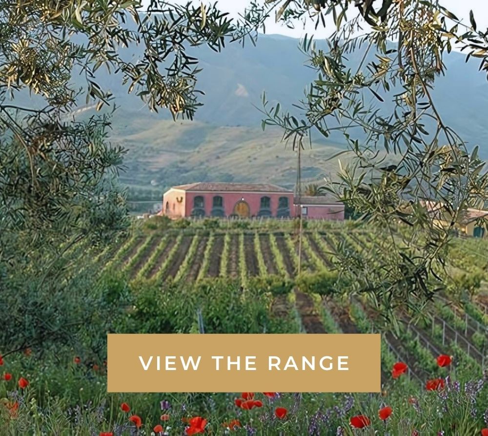 Vineyard with olive branches in foreground, villa in the distance, "VIEW THE RANGE" text overlay.