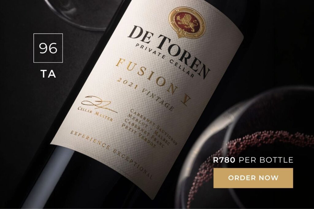 Close-up of De Toren Fusion V 2021 vintage red wine bottle with a filled glass, priced at R780 per bottle.