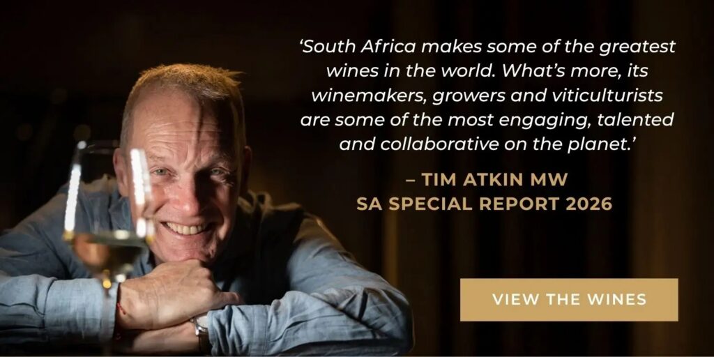Smiling man resting on folded arms with wine glass in foreground and quote praising South African winemakers by Tim Atkin MW.